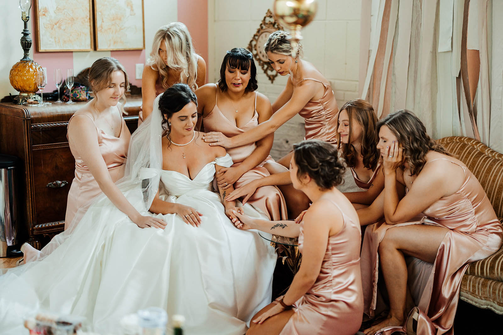 Cheney Place wedding photographer Grand Rapids Michigan candid bridesmaids in blush satin gowns surrounding emotional bride getting ready together, best documentary wedding photography West Michigan