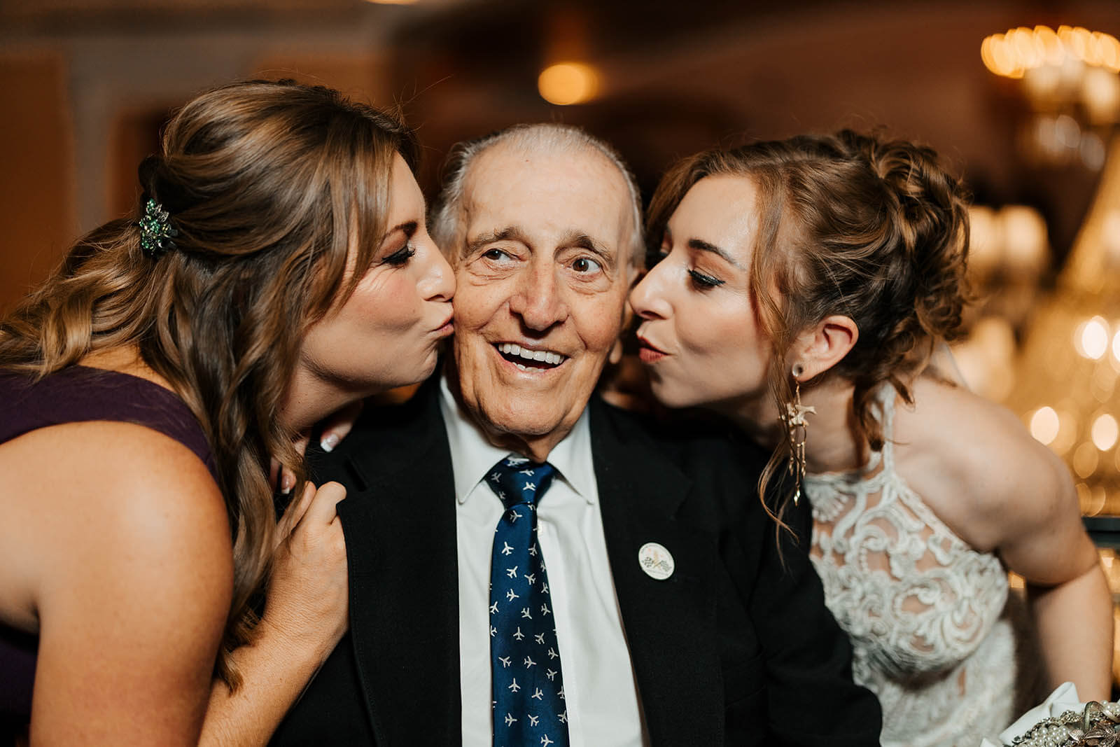 Amway Grand Plaza wedding photographer Grand Rapids Michigan candid bride and bridesmaid double kissing grandfather on cheeks at reception, top luxury West Michigan wedding photography