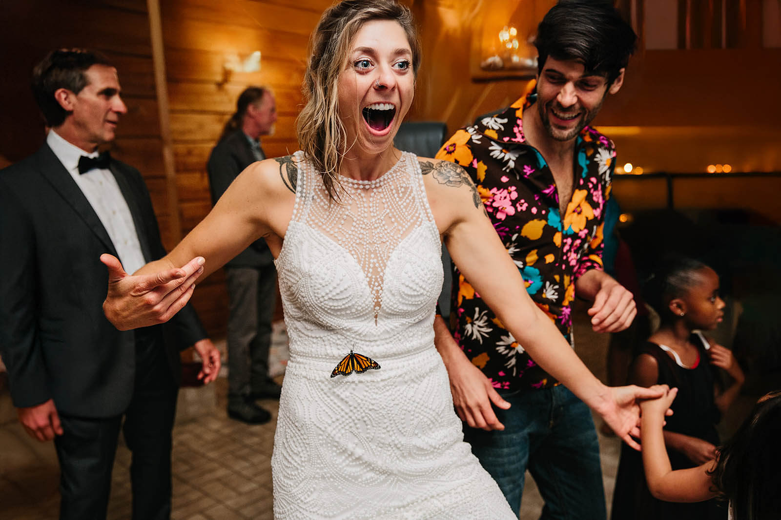 Documentary wedding photographer Goshen Indiana candid bride shocked by monarch butterfly landing on her dress while dancing at reception, top Indiana wedding photography GAUPERphoto