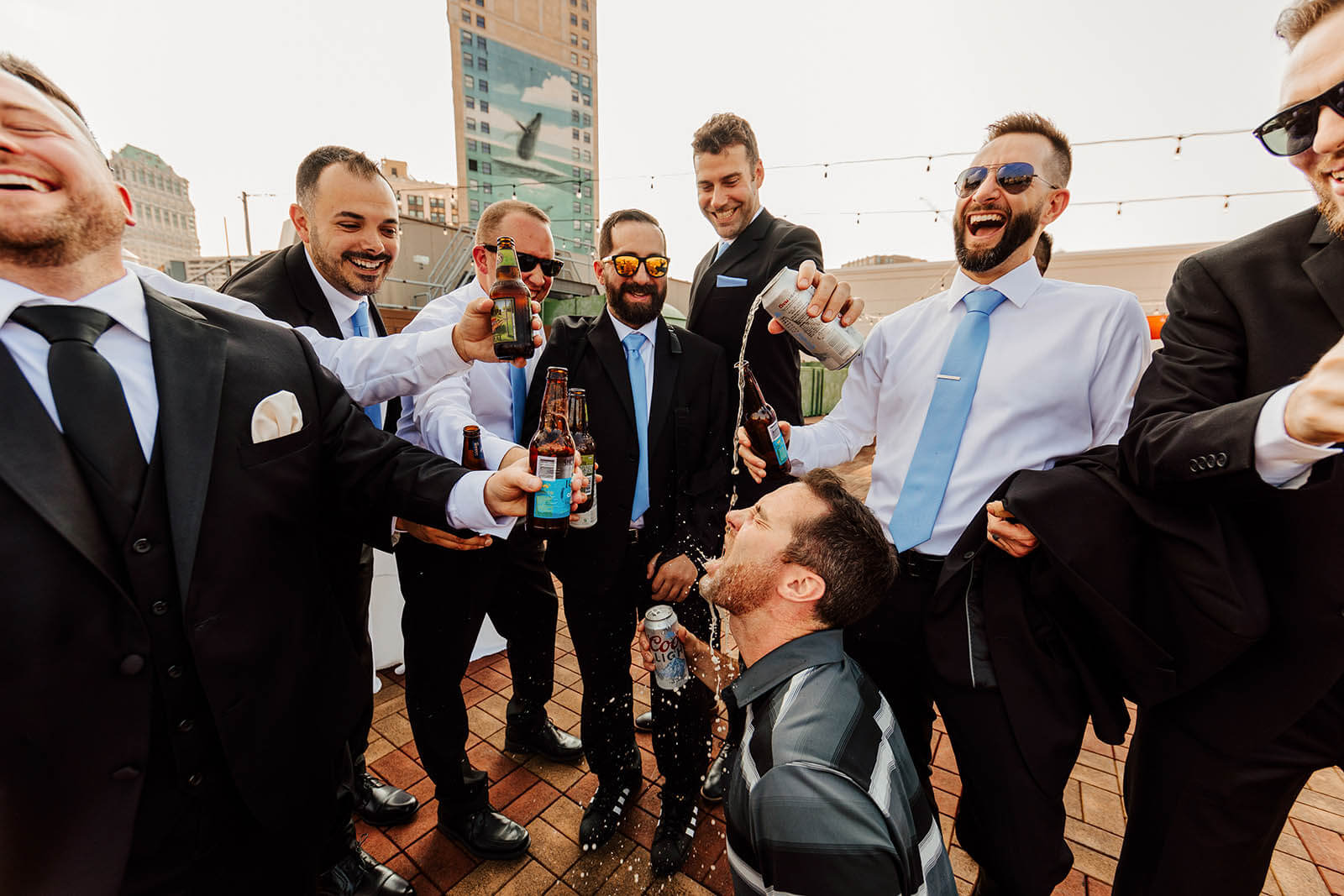 Detroit Opera House wedding photographer candid groomsmen pouring beer on each other celebrating on rooftop, best documentary Detroit Michigan wedding photography