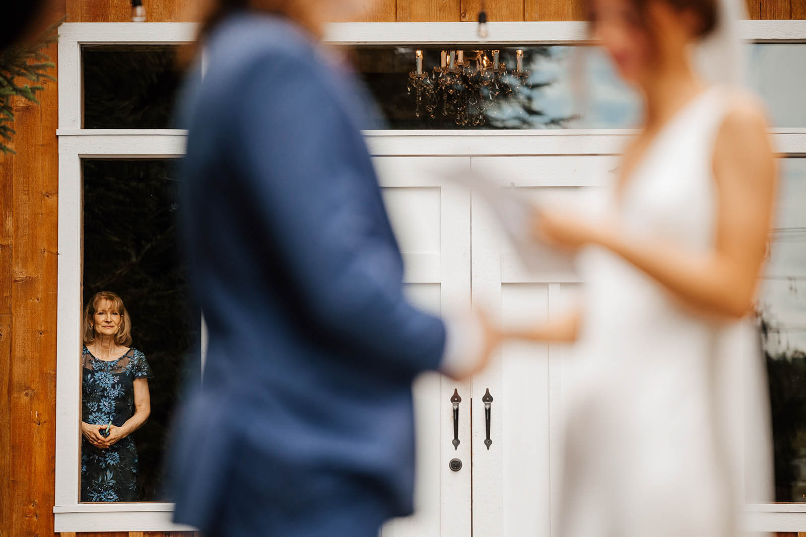 Pine Tree Barn wedding photographer Flushing Michigan candid mother watching through window with tears as bride and groom exchange vows, best documentary Michigan wedding photography