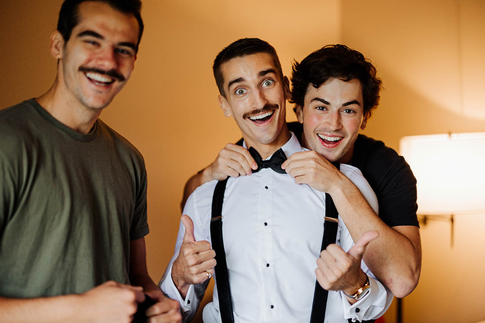 The Highlands wedding photographer Harbor Springs Michigan candid groom and groomsmen laughing together while fixing bow tie getting ready, top Northern Michigan documentary wedding photography GAUPERphoto
