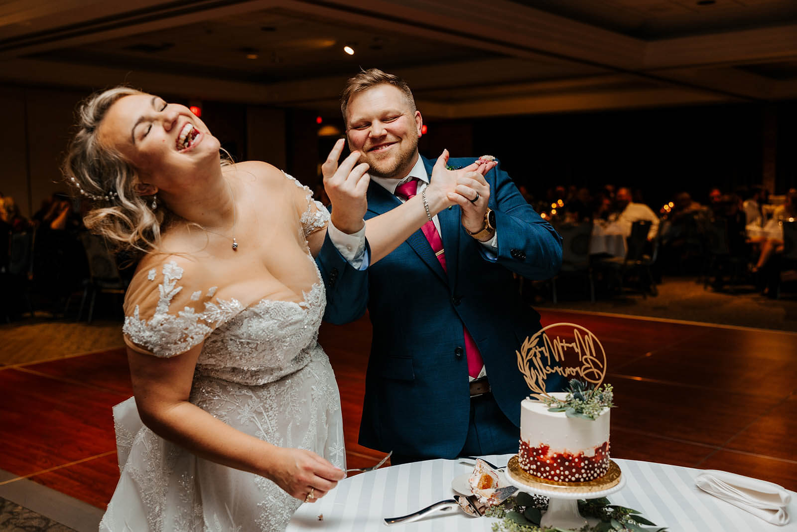 LV Eberhard Center wedding photographer Grand Rapids Michigan candid bride and groom laughing during cake smash at wedding reception, best luxury West Michigan wedding photography GAUPERphoto