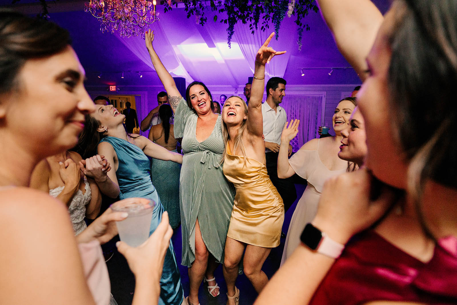 Castle Farms wedding photographer Charlevoix Michigan candid wedding guests dancing with arms raised under purple reception lighting, top Northern Michigan luxury wedding photography GAUPERphoto