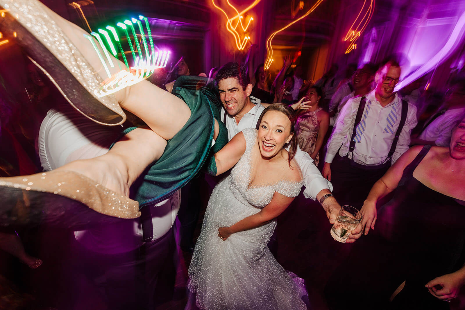 Candid bride dipping on dance floor under neon lights at Colony Club wedding in Detroit Michigan