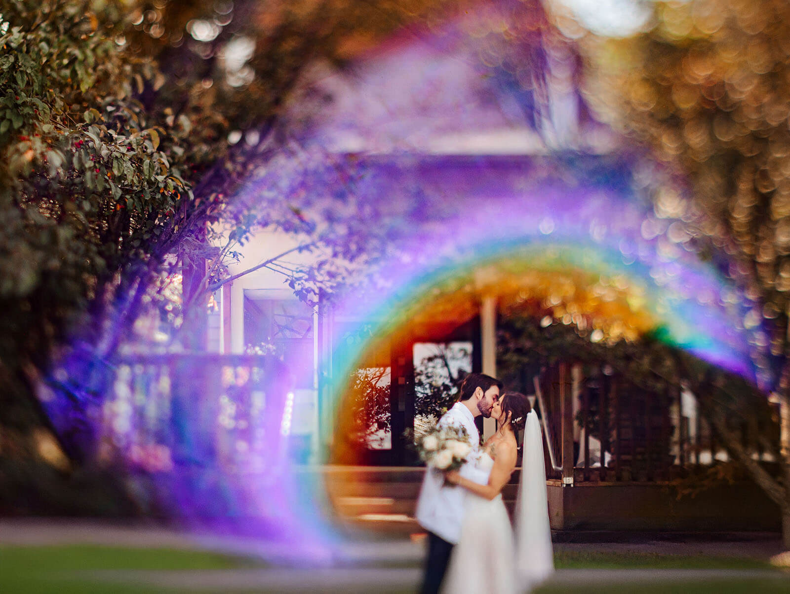 Bride and groom kiss framed by rainbow lens flare at Timberlee Hills wedding in Traverse City Michigan
