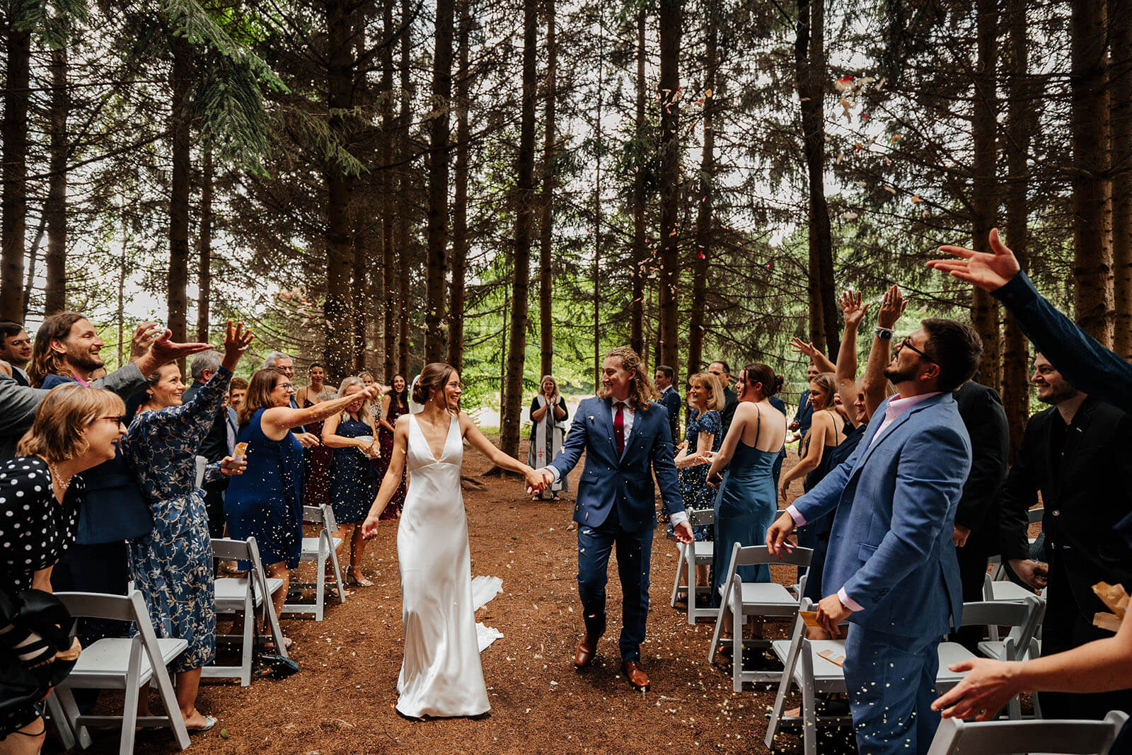 Confetti recessional in pine forest ceremony at Pine Tree Barn wedding in Flushing Michigan