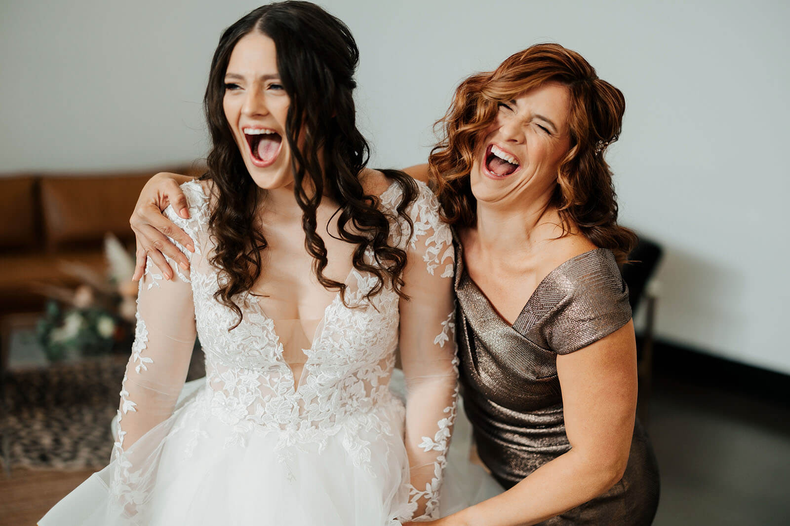 Candid bride and mother laughing during getting ready in lace gown at Leona Road wedding in Grand Rapids Michigan