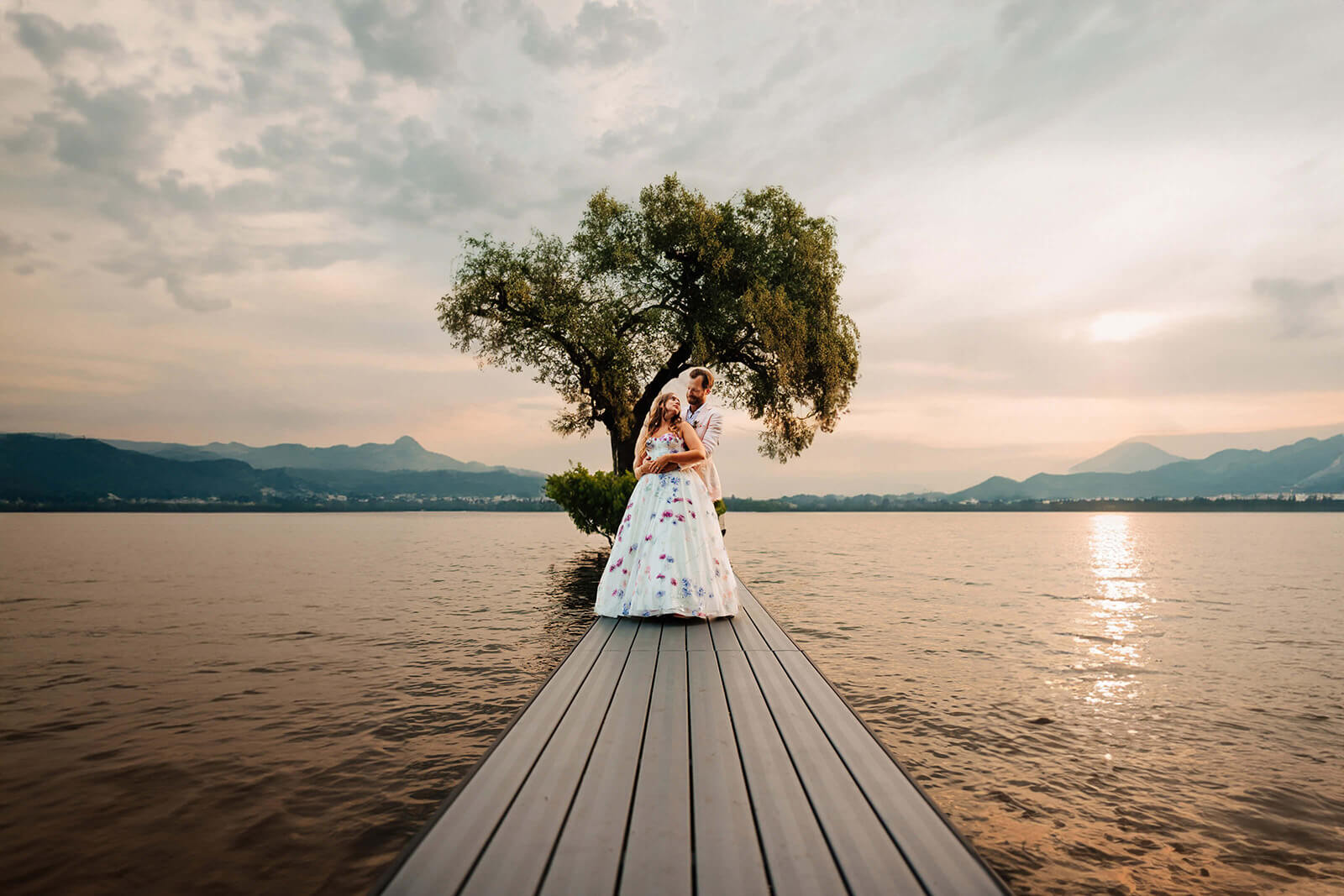 Bride and groom on dock at sunset with colorful gown and lake reflection in Flushing Michigan