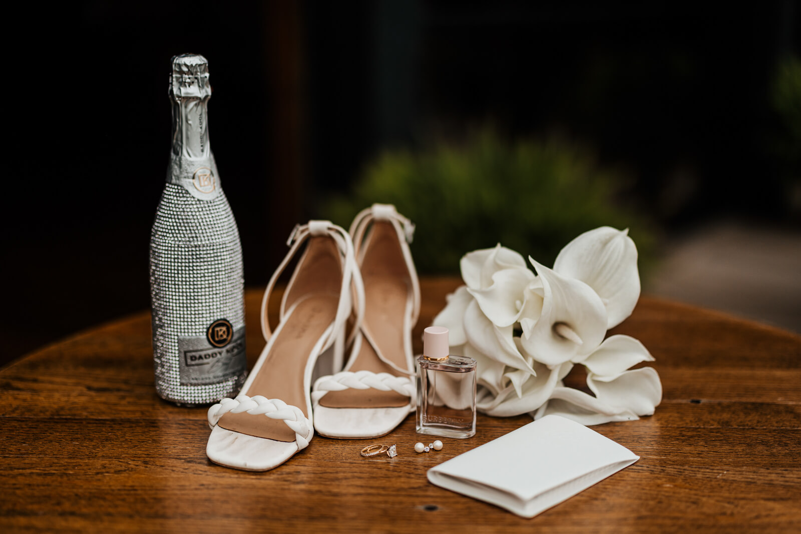 Bridal accessories flat lay with champagne bottle, heels, and wedding day details