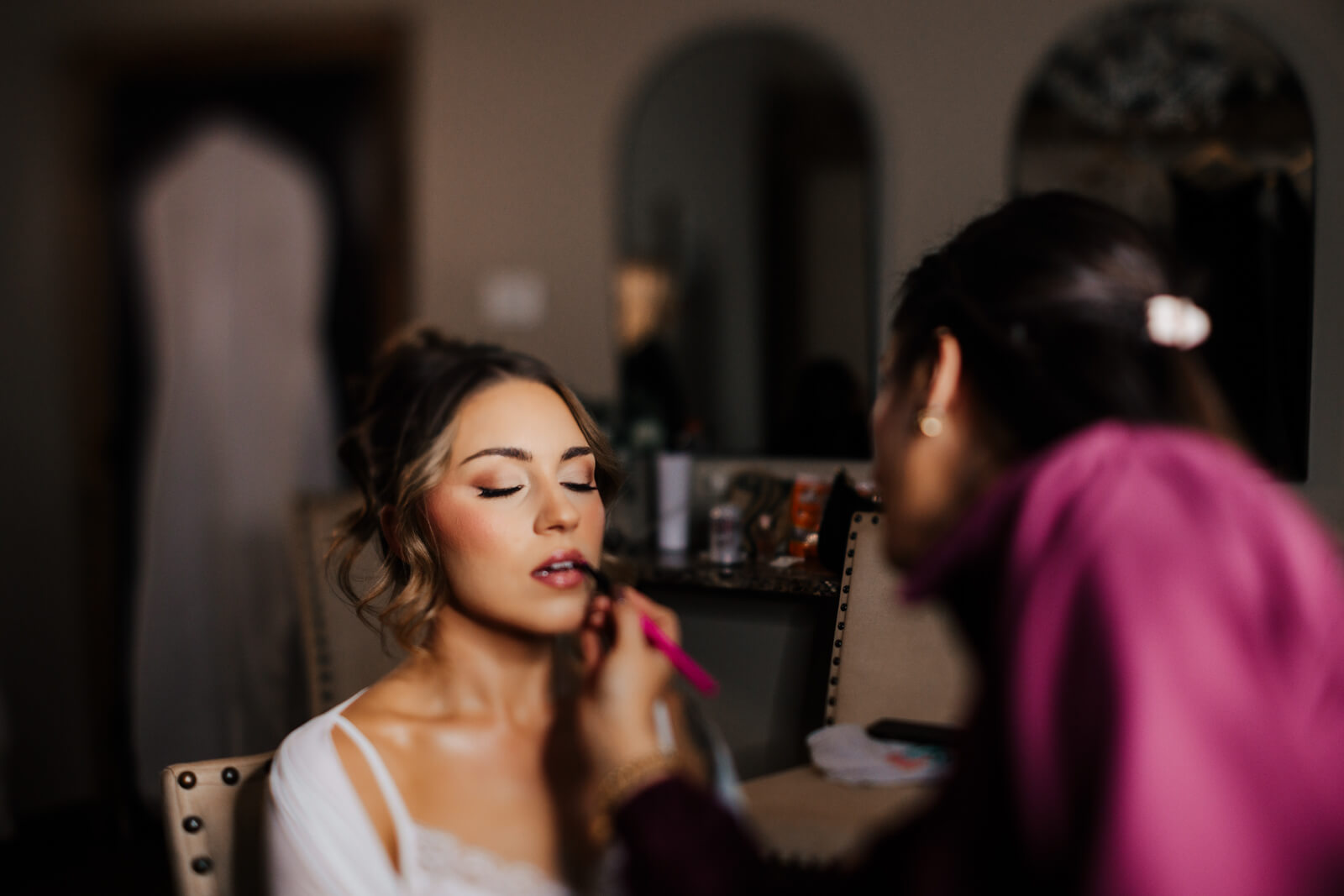 Bride getting makeup applied during wedding morning preparations