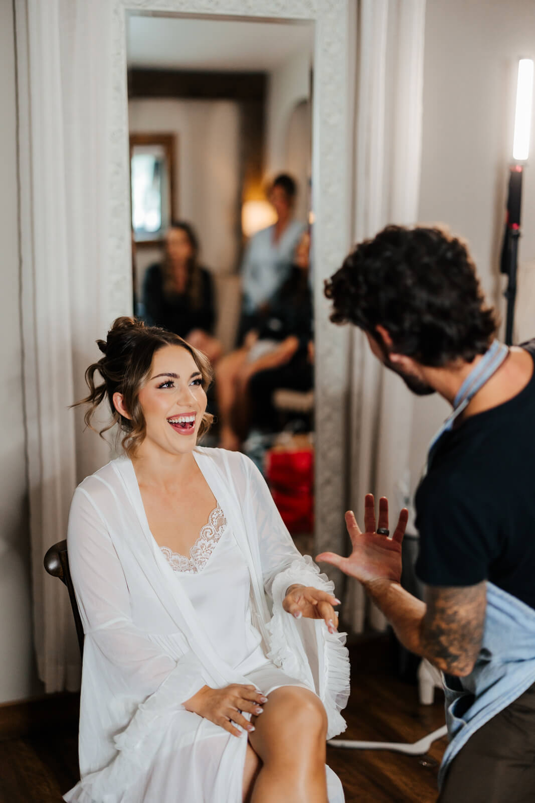 Bride laughing while getting hair styled on wedding morning