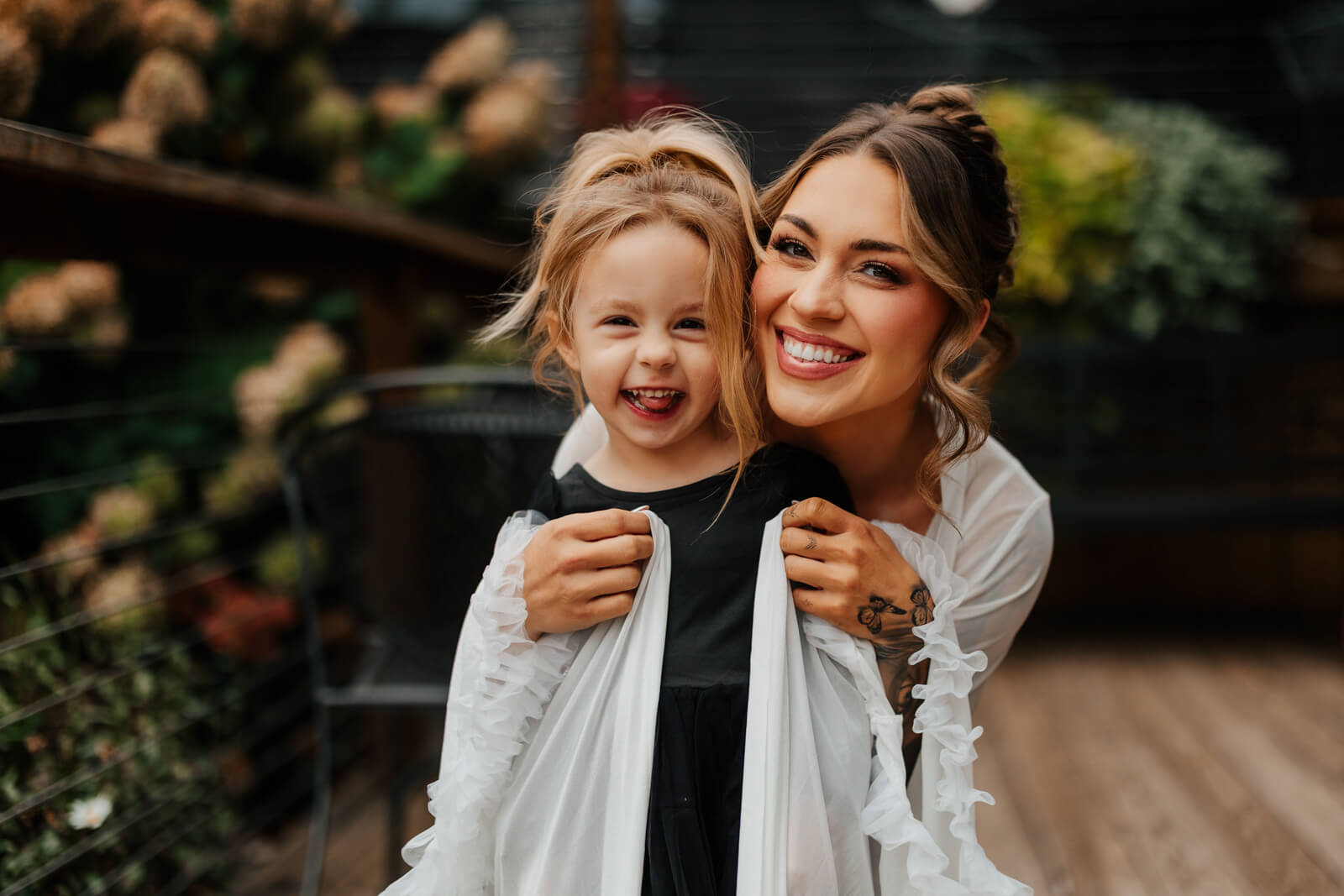 Bride hugging and laughing with flower girl on wedding morning