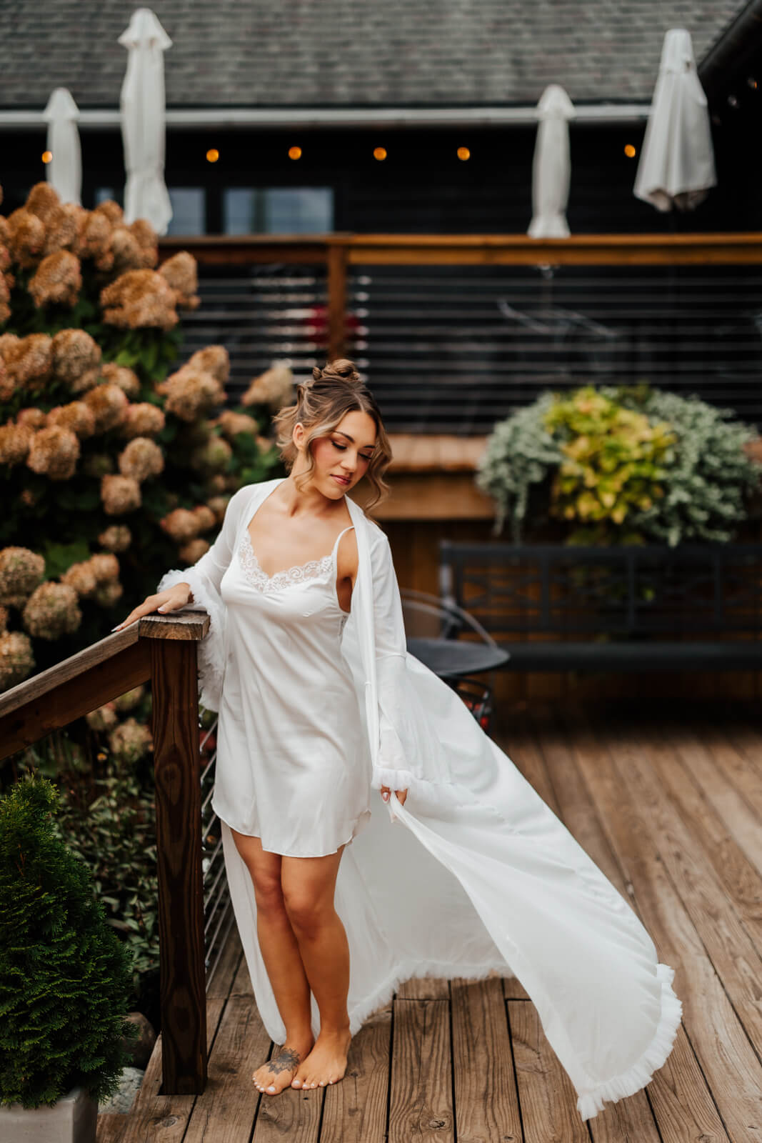 Bride in white robe on deck surrounded by hydrangeas at Westers Family Winery