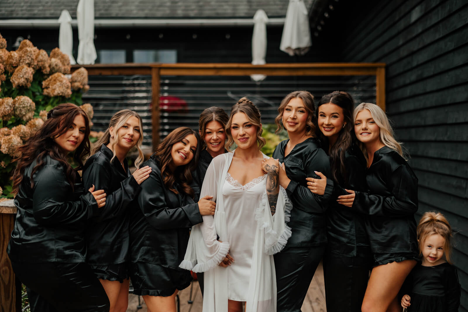 Bride with bridesmaids in black robes laughing together with hydrangeas at Westers Family Winery