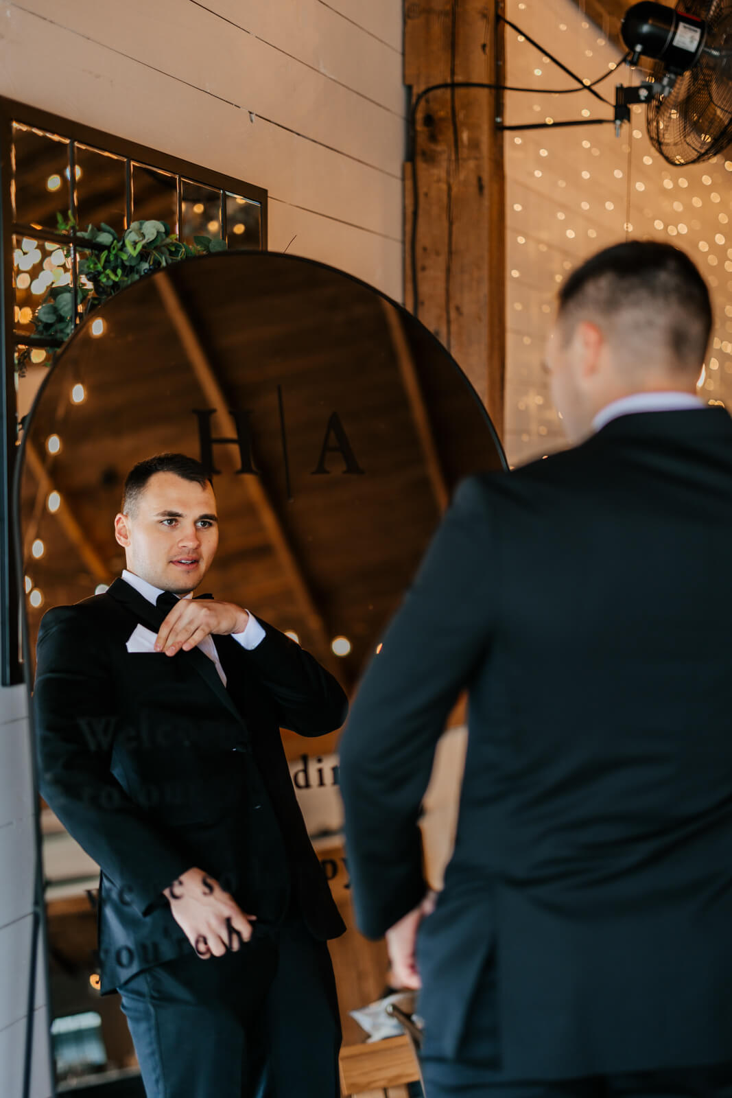 Groom helping with boutonniere during wedding morning preparations