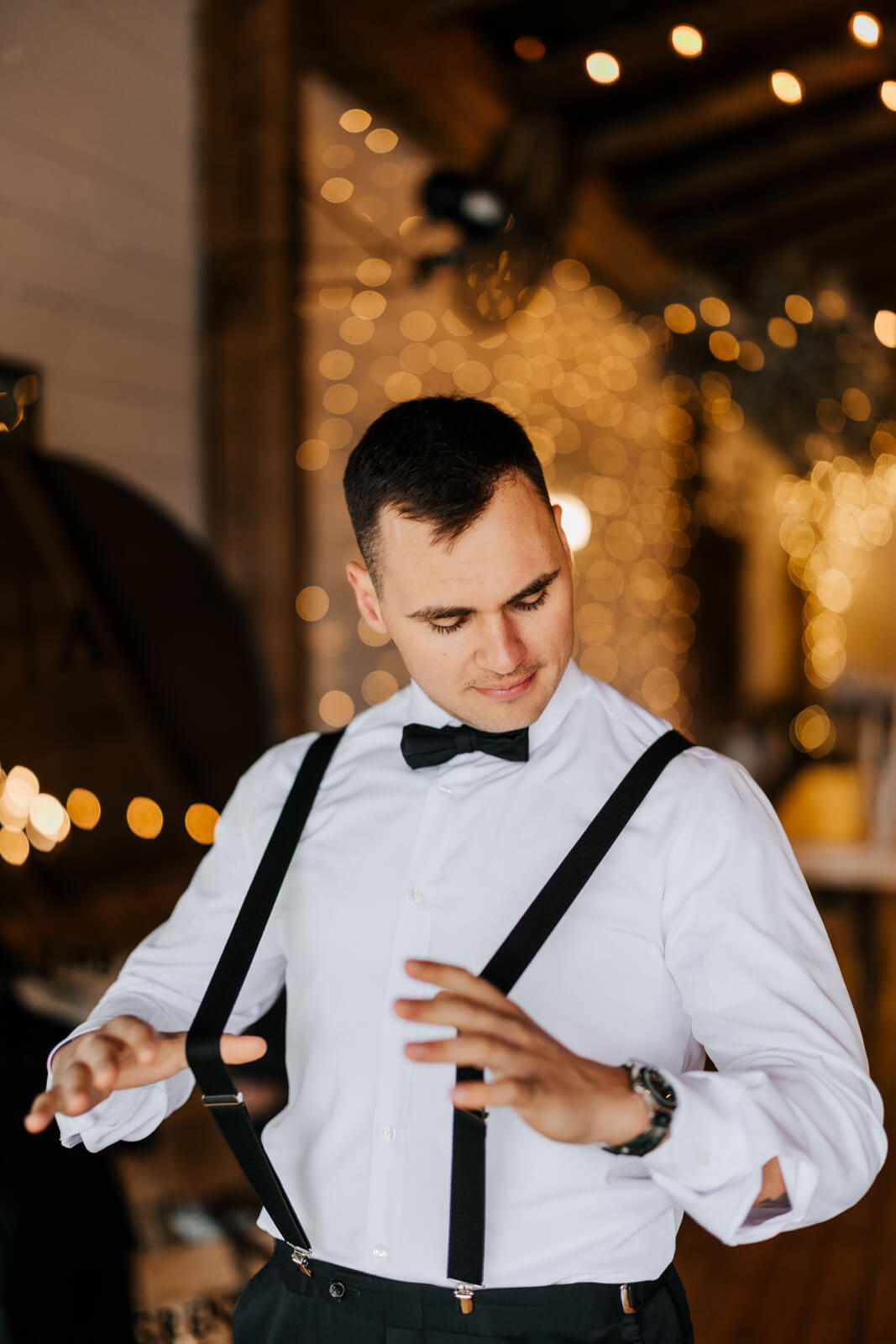 Groom in tuxedo adjusting suspenders before fall wedding ceremony