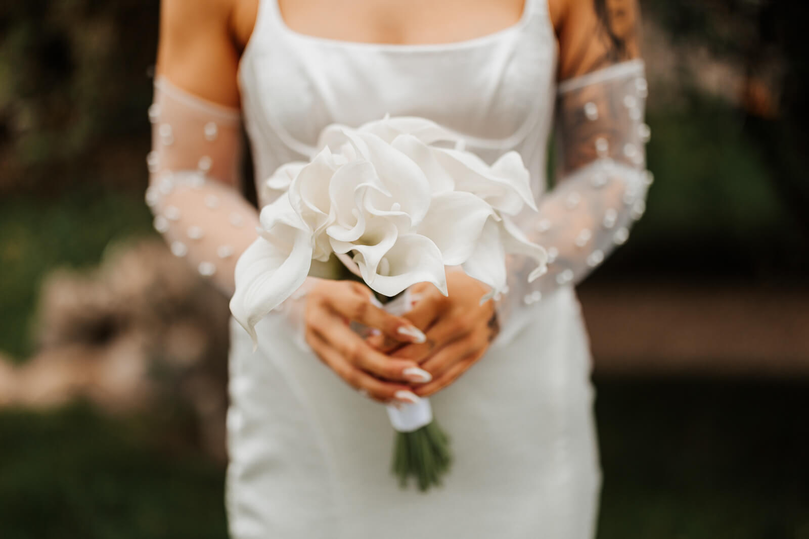 Close-up of bride holding white calla lily wedding bouquet
