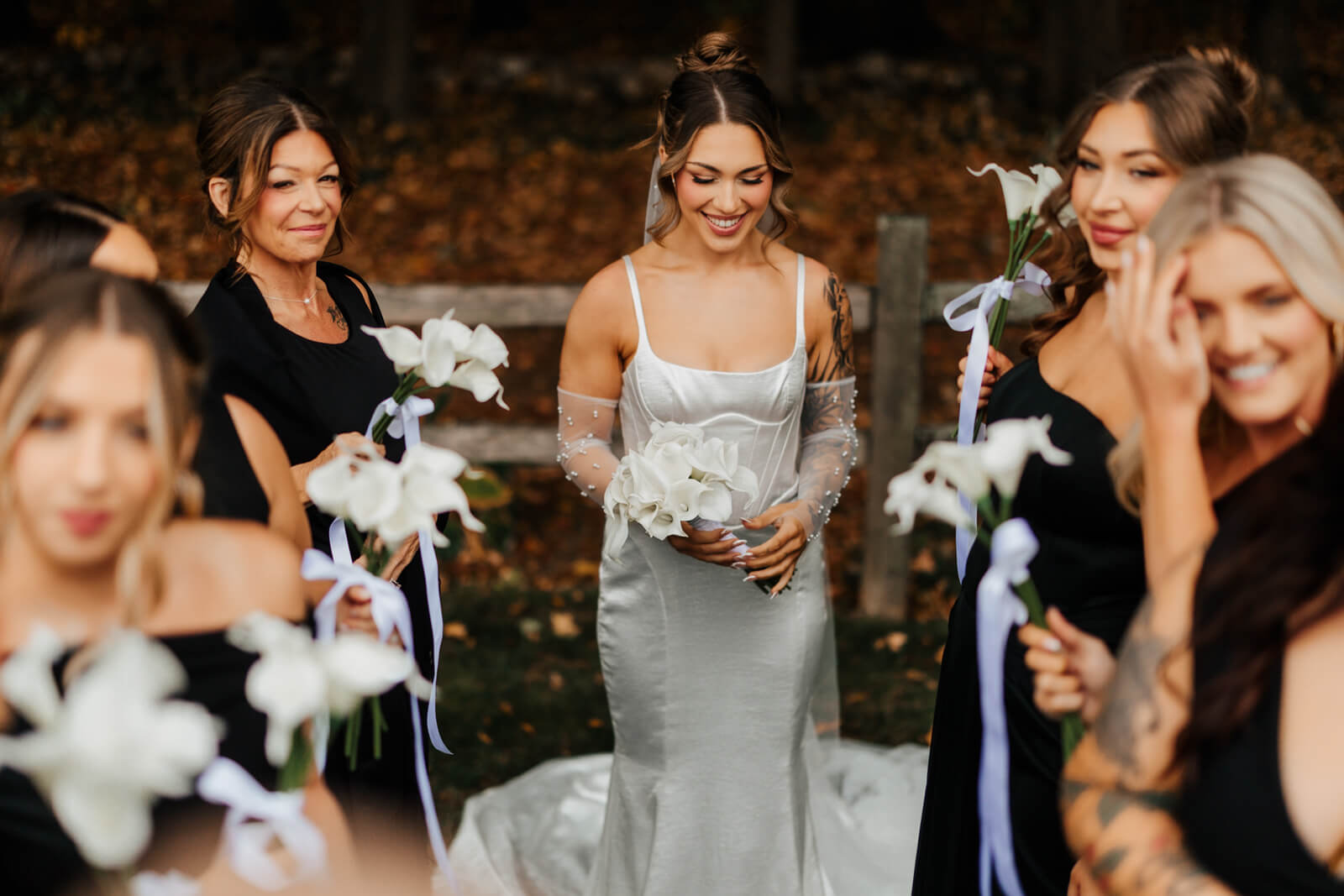 Bride laughing with bridesmaids holding white calla lilies at October Michigan wedding