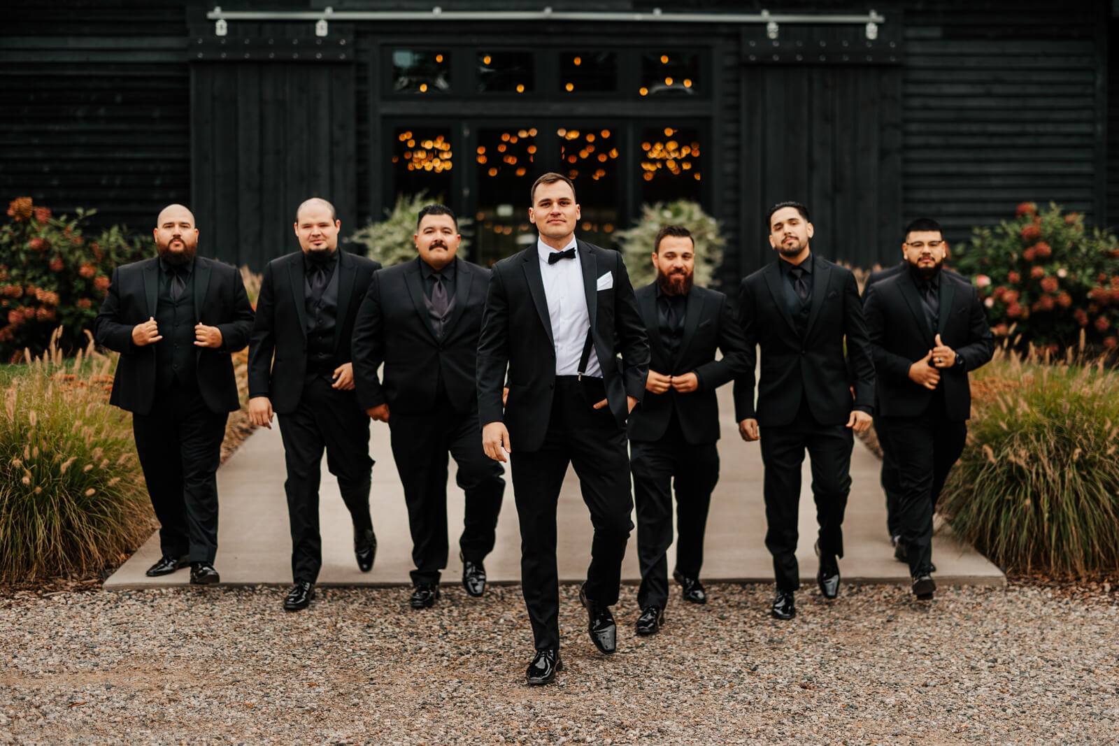 Groom and groomsmen all in black tuxedos walking together at Westers Family Winery