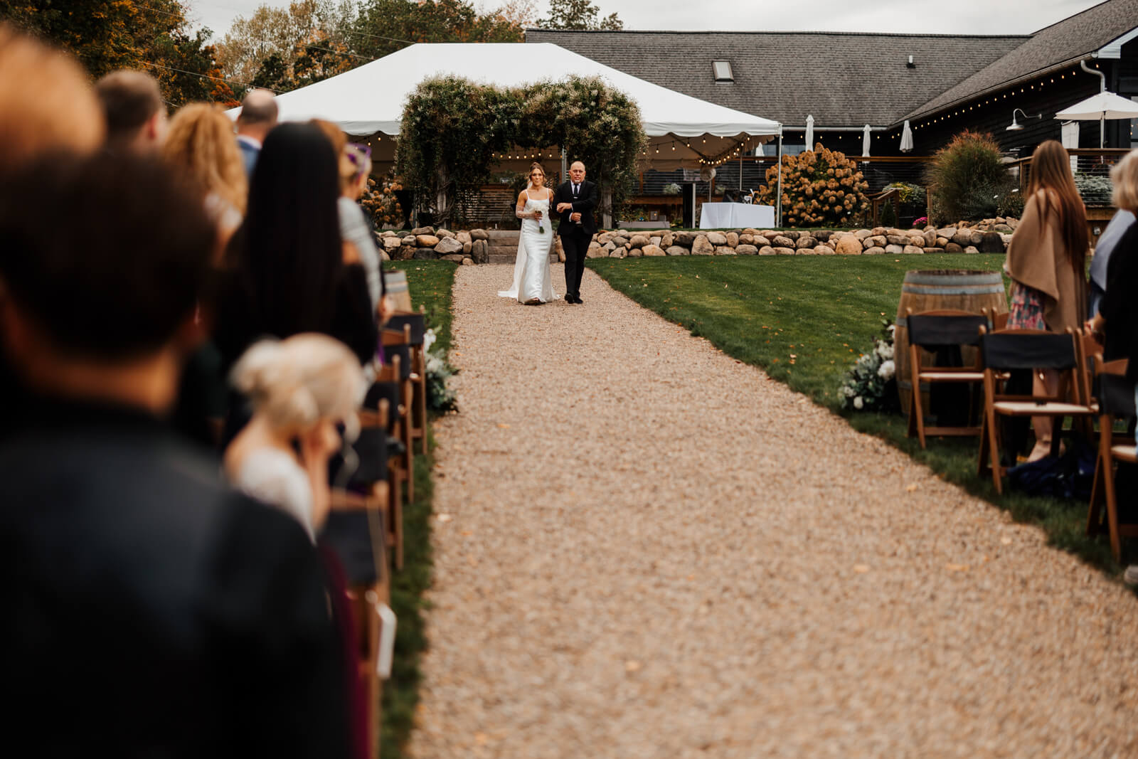 Bride walking down outdoor ceremony aisle toward arch at Westers Family Winery