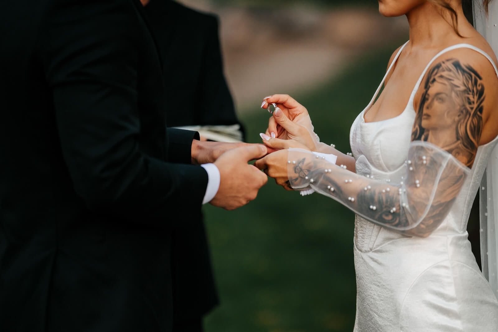 Bride placing wedding ring on groom's finger during fall wedding ceremony