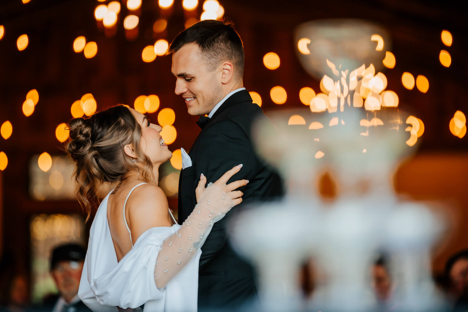 Bride and groom first dance under string lights with champagne tower at Westers Family Winery reception