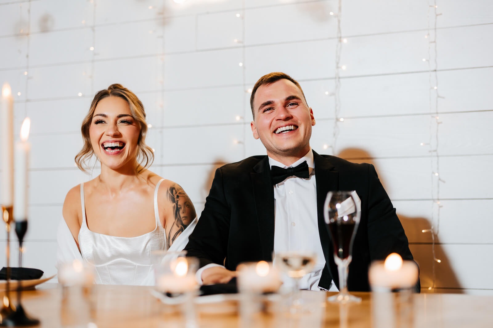 Bride and father laughing together at table during wedding speeches at winery reception