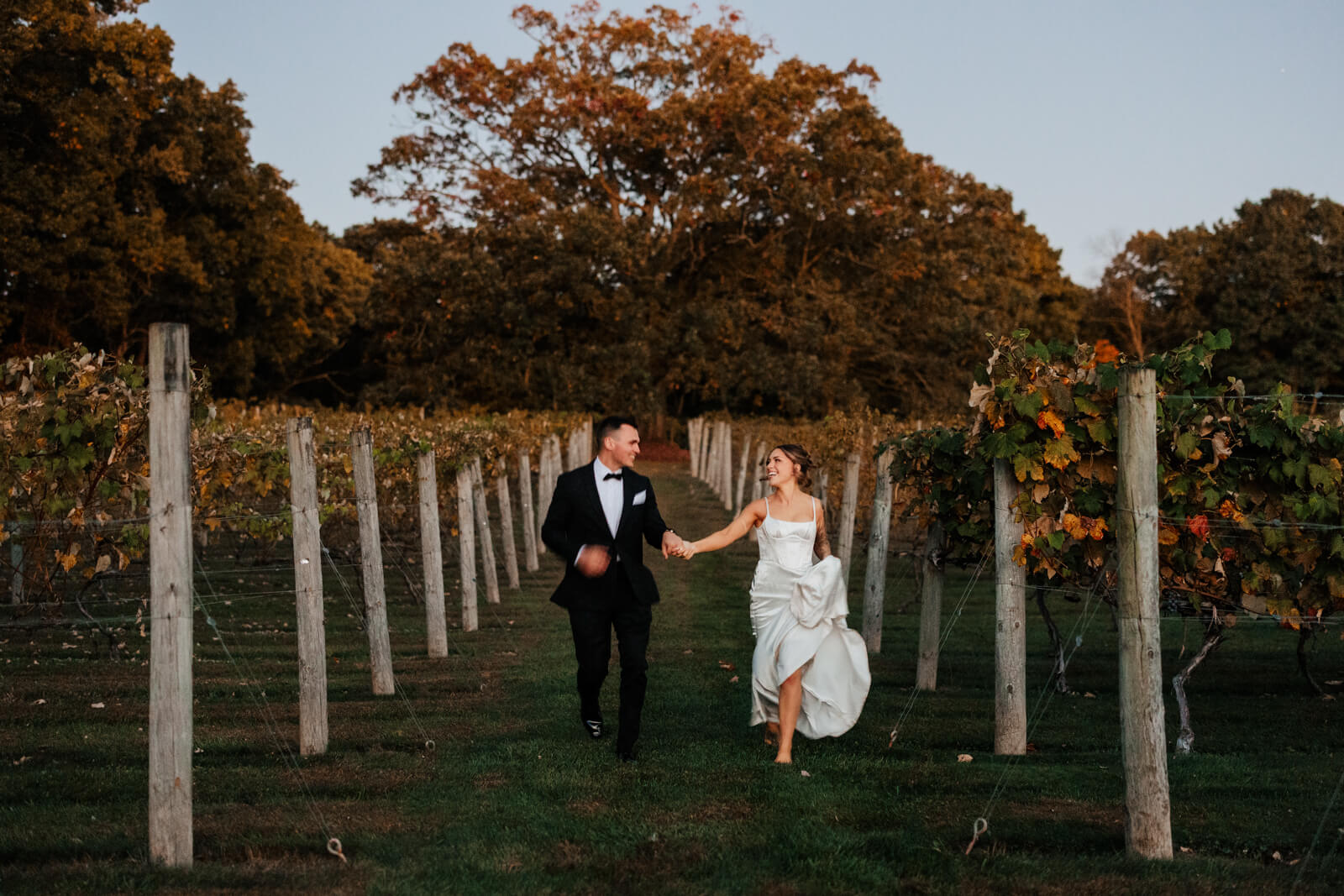 Bride and groom running through vineyard