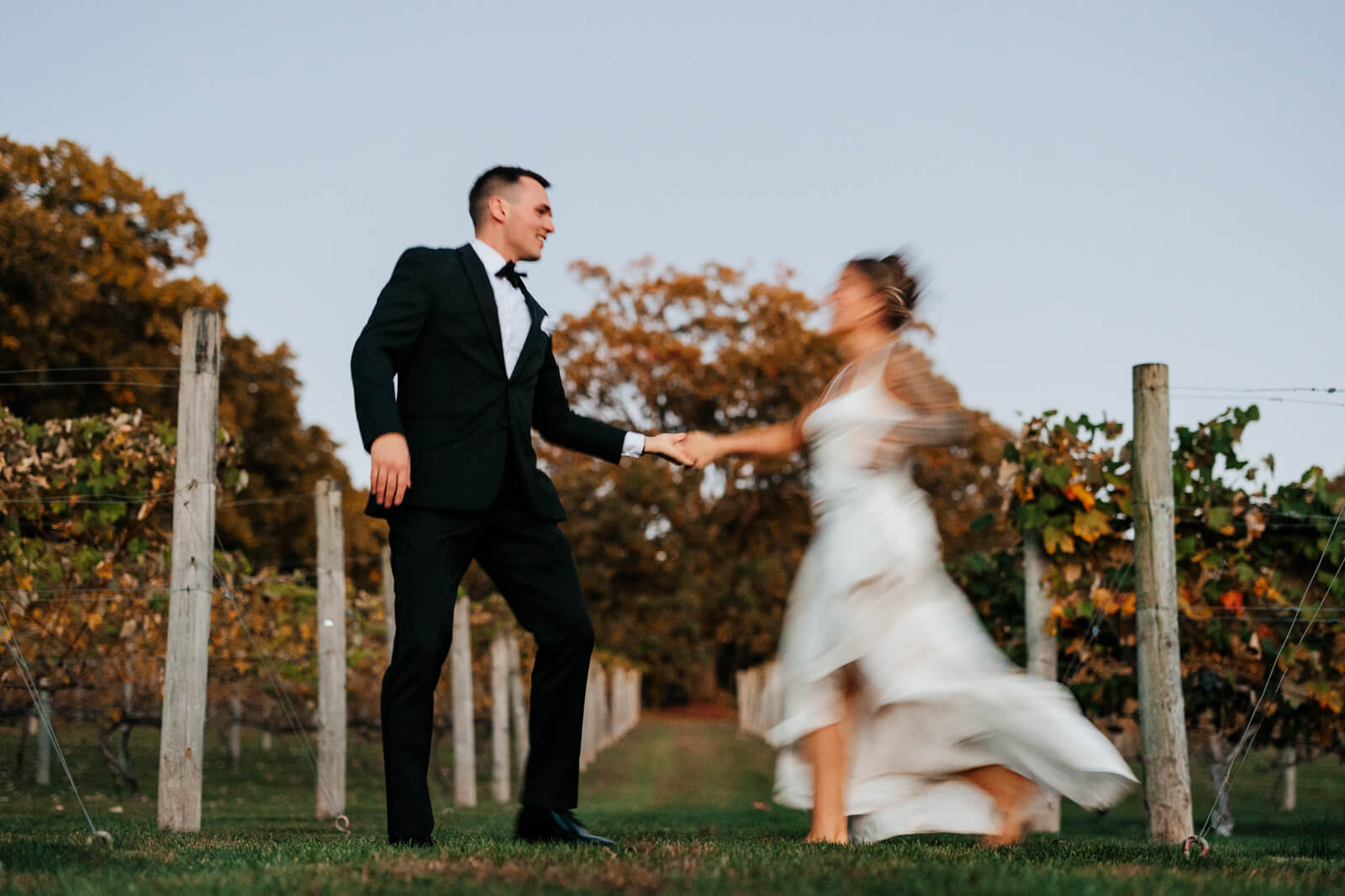 Bride and groom twirling and dancing in vineyard rows at golden hour at Westers Family Winery