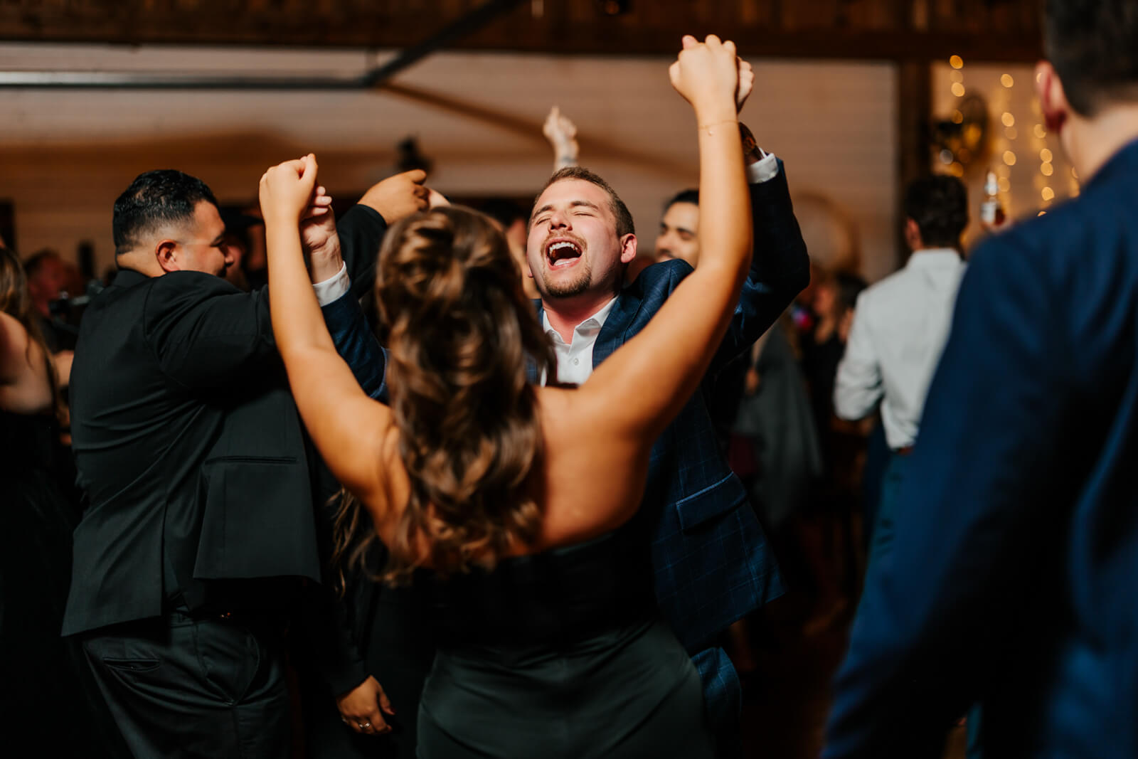 Wedding guests dancing with arms up celebrating at Westers Family Winery fall reception