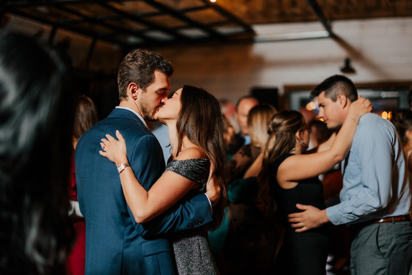 Couples slow dancing together on crowded dance floor at fall winery wedding reception
