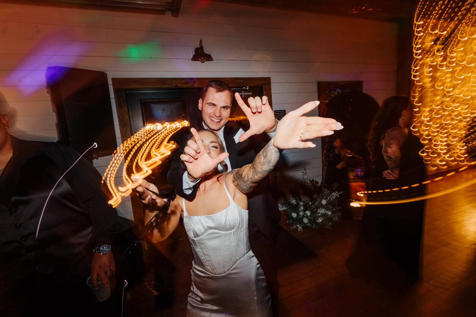 Bride and groom throwing up rock-on hands with light painting effect on dance floor at winery wedding