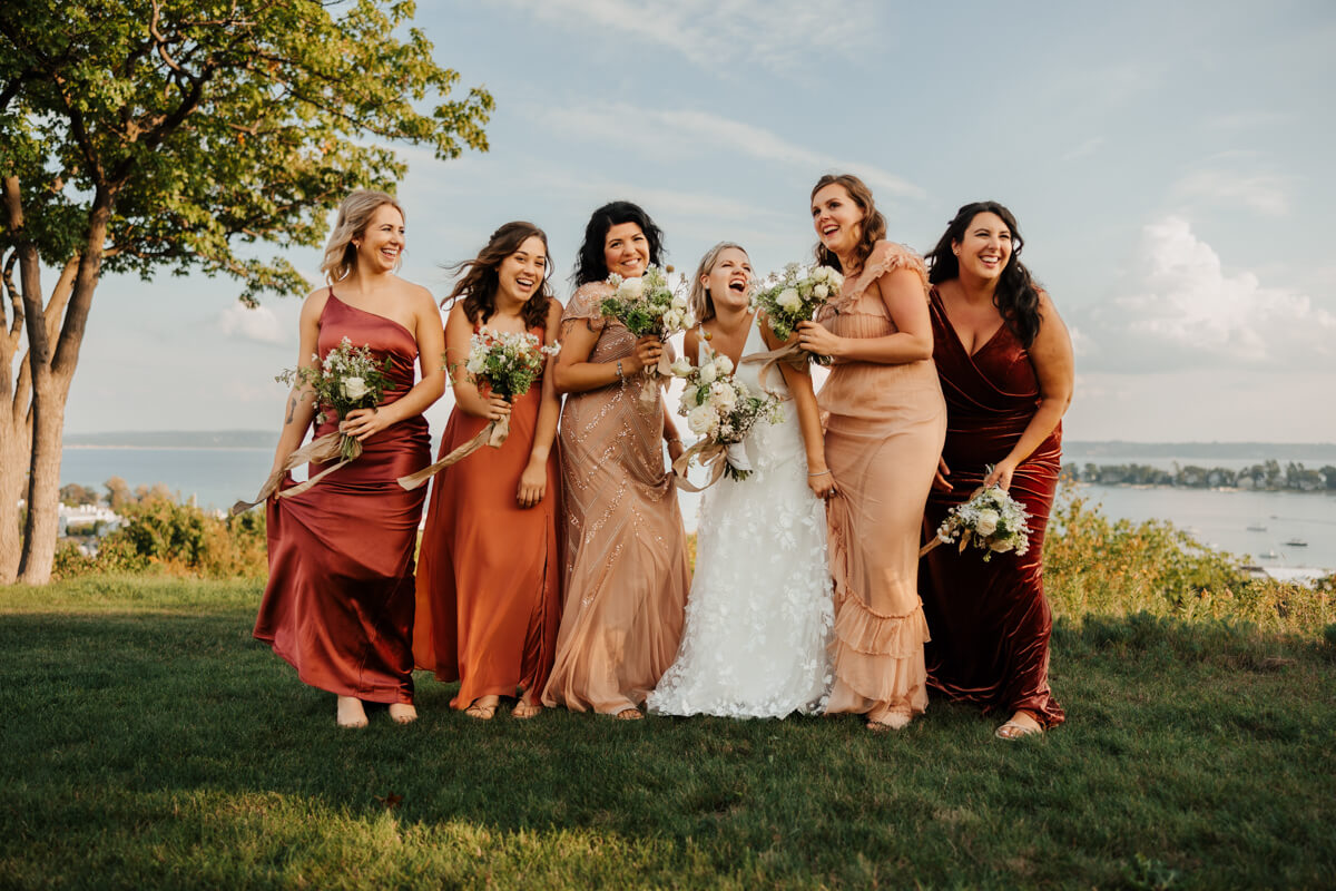 Bridal party in warm earth tones laughing together outdoors at Michigan wedding