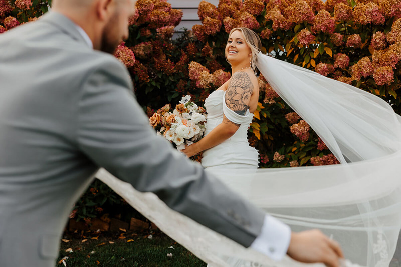Bride and groom portrait with veil blowing in the wind at Michigan wedding