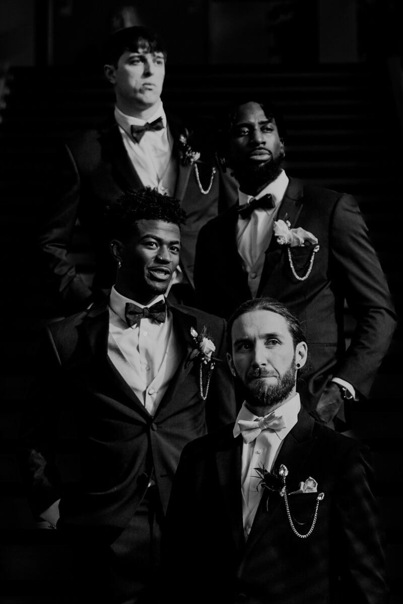 Dramatic black and white portrait of groomsmen in tuxedos on staircase at Grand Rapids wedding