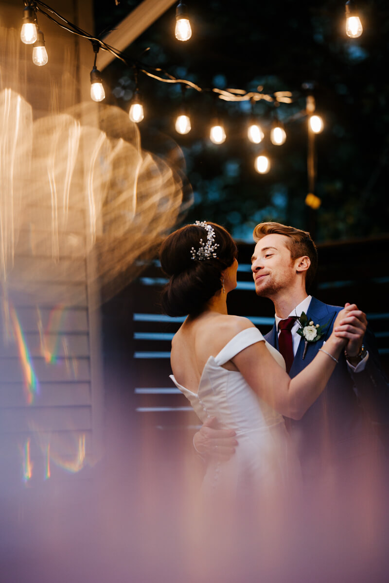 Bride and groom sharing first dance under Edison string lights at night outdoor Grand Rapids wedding